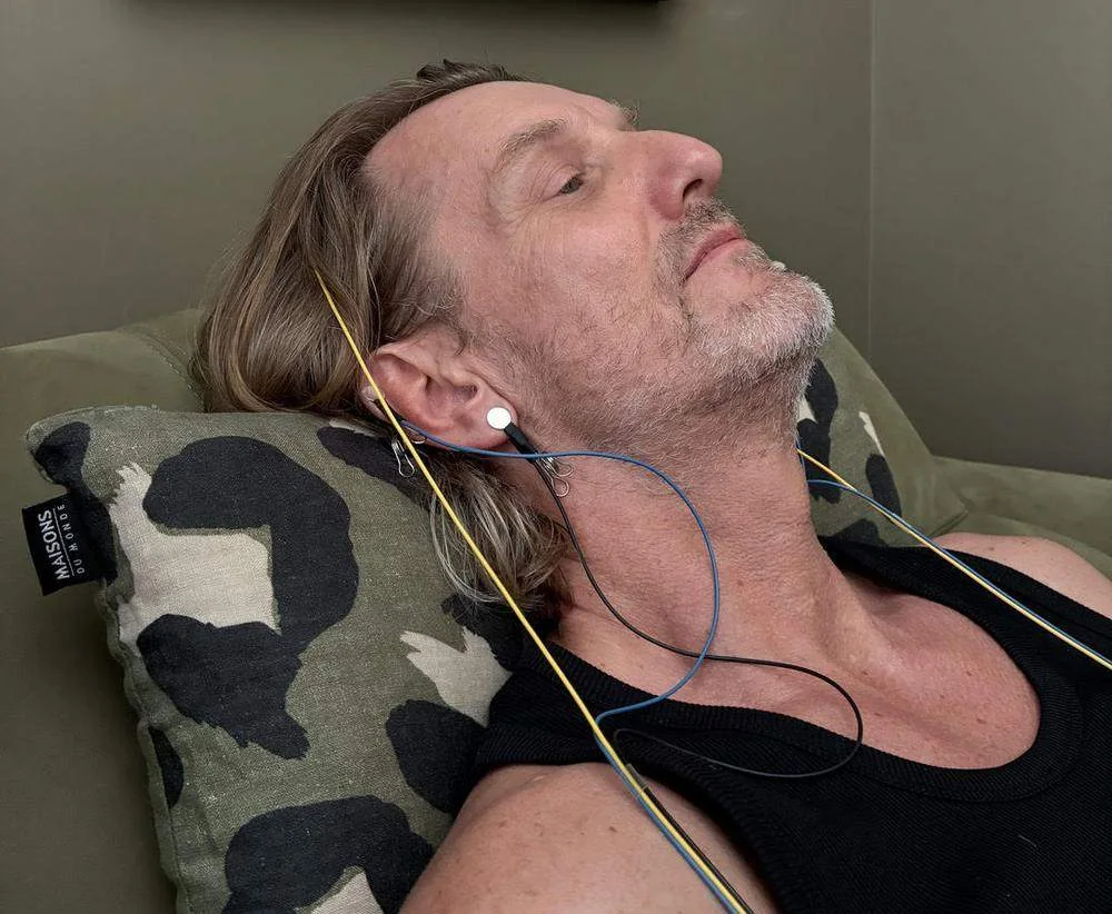 Capteurs de Neurofeedback posés sur l'oreille d'un homme allongé, détendu, pendant une séance