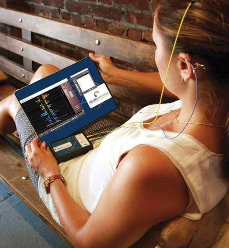 Femme assise sur un banc avec la tablette et le boîtier NeurOptimal®