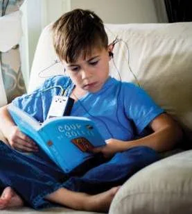 Garçon qui lit un livre pendant sa séance, capteurs en place